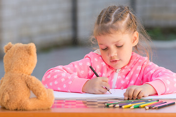 Image showing The girl with enthusiasm draws with crayons in the album