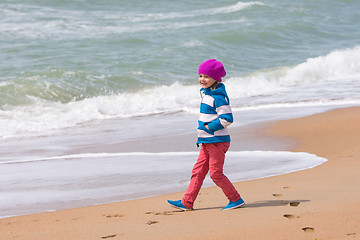 Image showing Happy girl walking along coastal sea beach on a warm spring day