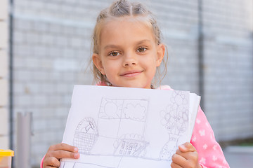 Image showing A girl shows a drawing, drawn in pencil