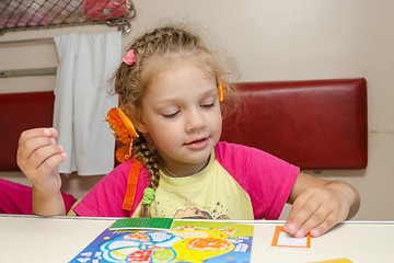 Image showing Little girl on the train sits at a table on the lower second-class place car and enthusiastically skin application