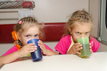 Image showing Two children drink tea in train at the table on the lower place in the second-class compartment wagon