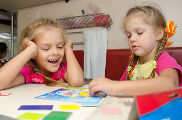 Image showing Two girls having fun playing on the train at the table on the lower place in the second-class compartment wagon