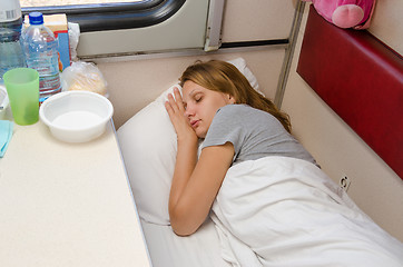 Image showing The girl on the train is fast asleep at a lower second-class place car coupe