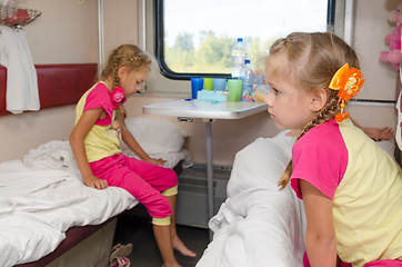 Image showing Two girls sisters on the train on the lower ground in the second-class compartment wagon