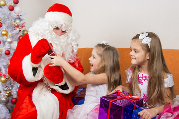 Image showing Santa Claus gives presents two sisters