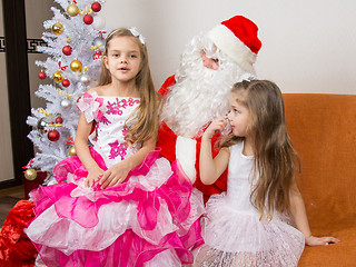 Image showing The older girl is sitting on the lap of Santa Claus and tells poem