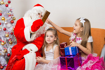 Image showing Santa Claus gives gifts to one girl, the other sitting in the waiting
