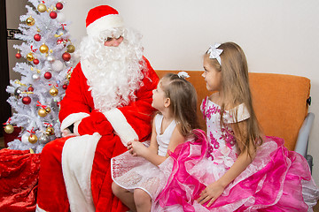 Image showing Two girls in beautiful dresses talk with Santa Claus