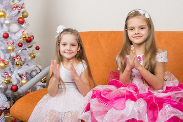 Image showing Two girls in beautiful dresses guessing gifts for the new year