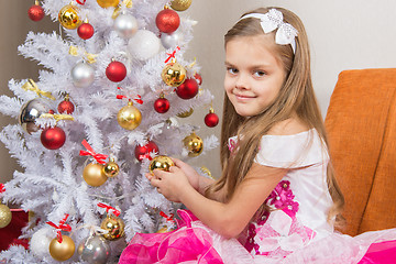 Image showing Seven-year girl in a beautiful dress treats Christmas toys and looked into the frame