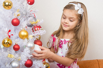 Image showing Seven-year girl in a beautiful dress treats Christmas toys