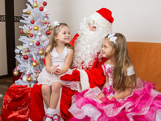 Image showing Little girl sitting on the lap of Santa Claus and tells poem