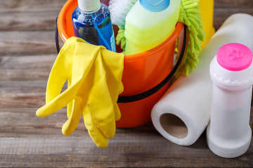 Image showing Plastic bucket with cleaning supplies on wood background