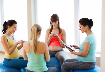 Image showing happy pregnant women with gadgets in gym