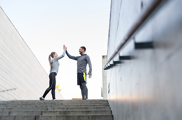 Image showing smiling couple making high five on city street