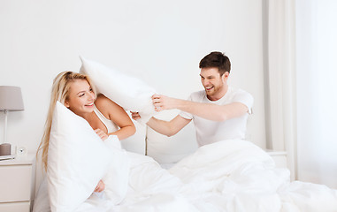 Image showing happy couple having pillow fight in bed at home