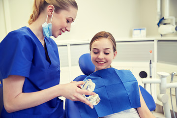Image showing happy dentist showing jaw model to patient girl