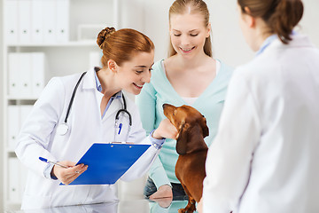 Image showing happy woman with dog and doctor at vet clinic