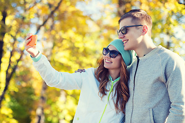Image showing smiling couple with smartphone taking selfie