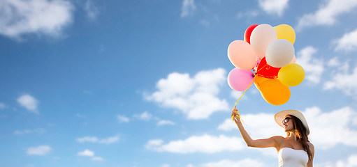 Image showing smiling young woman in sunglasses with balloons