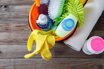 Image showing Plastic bucket with cleaning supplies on wood background