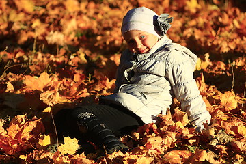 Image showing little girl laying in yellow leaves