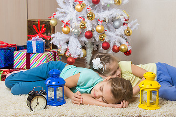 Image showing Two girls slept through the whole New Years Eve at the Christmas tree while waiting for the arrival of Santa Claus and gifts