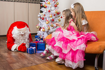 Image showing Two girls saw that Santa Claus puts presents under the Christmas tree
