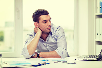 Image showing bored businessman with laptop and papers at office