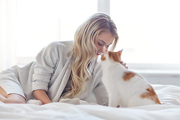 Image showing happy young woman with cat in bed at home