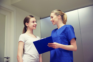 Image showing smiling nurse with clipboard and girl at hospital