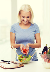 Image showing smiling woman cooking vegetable salad at home