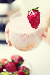 Image showing close up of hand holding glass with fruit shake