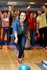 Image showing happy young woman throwing ball in bowling club