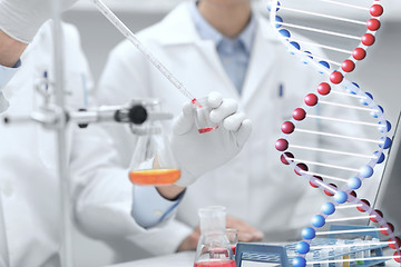 Image showing close up of scientists filling test tube in lab