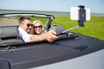 Image showing happy couple in car taking selfie with smartphone