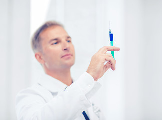 Image showing male doctor holding syringe with injection