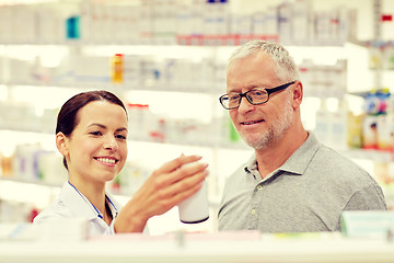 Image showing pharmacist showing drug to senior man at pharmacy