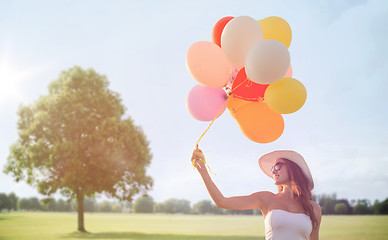 Image showing smiling young woman in sunglasses with balloons