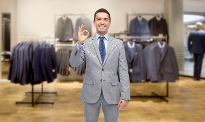 Image showing happy businessman in suit over clothing store