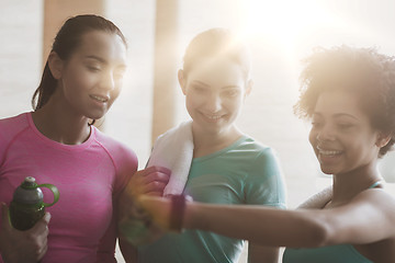 Image showing happy women showing time on wrist watch in gym