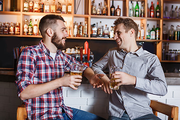 Image showing Happy friends drinking beer at counter in pub