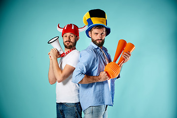 Image showing The two football fans with mouthpiece over blue