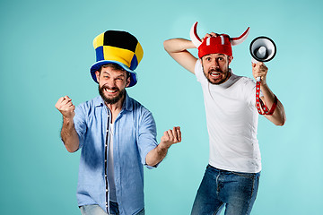 Image showing The two football fans with mouthpiece over blue