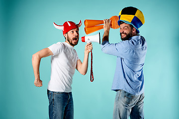 Image showing The two football fans with mouthpiece over blue