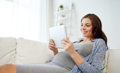 Image showing happy pregnant woman with tablet pc at home