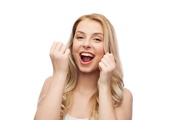 Image showing happy young woman with dental floss cleaning teeth