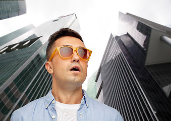 Image showing face of scared man in sunglasses over big city