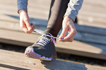 Image showing close up of sporty woman tying shoelaces outdoors