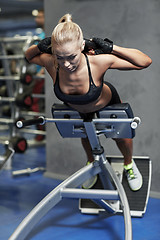 Image showing young woman flexing back muscles on bench in gym